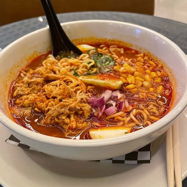 A bowl of Pretty Little Tacos ramen with chicken, corn, red onion, and a hard-boiled egg.